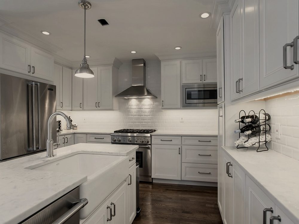 Renovated kitchen with custom cabinetry, a quartz island and tile backsplash