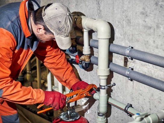 Plumber fitting supply lines to pipework in a mechanical room